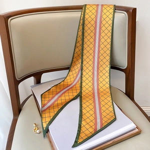 Détail d'un foulard en satin jaune à motif losanges drapé sur une chaise en cuir rétro
