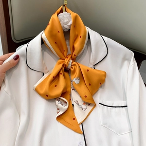 Close-up of orange silk scarf with rabbit print tied on a white pajama collar
