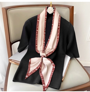 Dettaglio di un foulard in seta rosa a fiori su un top in maglia nera