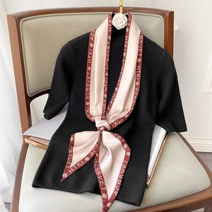 Dettaglio foulard in seta rosa e bordeaux con stampa di lettere su maglia nera
