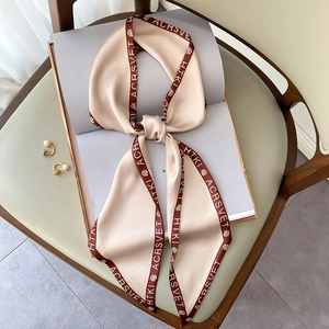 Sciarpa sottile in raso champagne con stampa rosa e bordo con lettere su libro