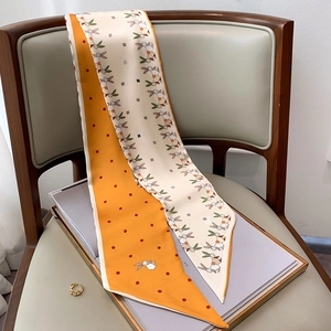 Detail of a dual-sided skinny scarf with orange dots and cute bunny patterns on a chair