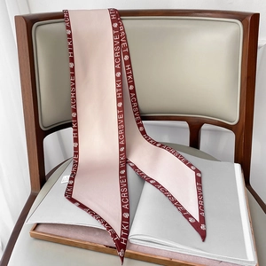 Dettaglio di una sciarpa in seta rosa con bordi bordeaux e stampe di lettere floreali