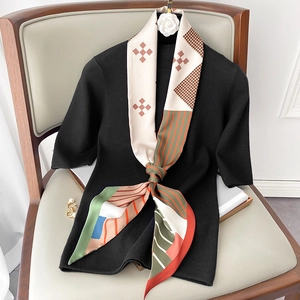 Detail of multi-patterned silk scarf with houndstooth and stripes on black knit top