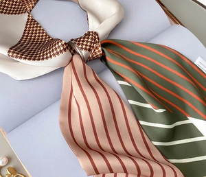 Close-up detail of luxury printed silk scarf showing houndstooth patterns and stitching