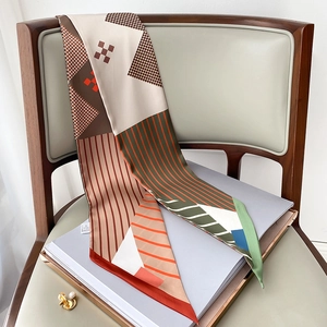 Detail of a geometric print skinny scarf draped on a chair with pearls as decoration