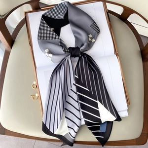 Detail of printed silk twilly scarf with houndstooth and stripe patterns on a white book