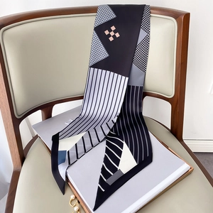Detailed view of houndstooth silk scarf with geometric patterns tied on a chair