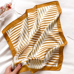 Detail of square silk scarf with chevron pattern in yellow and ivory on soft fabric