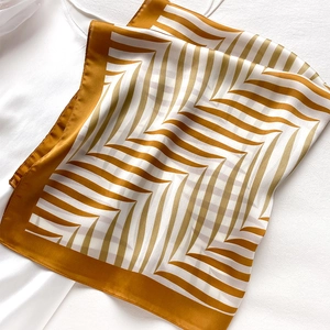 Detail view of the yellow and white geometric silk scarf with smooth satin texture