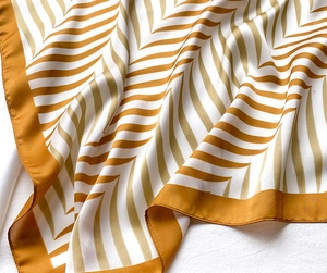 Detail of yellow and beige silk scarf showing chevron patterns and smooth texture