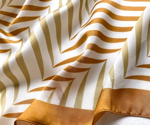 Close-up of golden chevron silk scarf showing premium satin texture and rolled hem edge