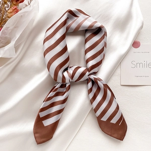 Elegant brown and white diagonal striped silk scarf styled with a knot on satin