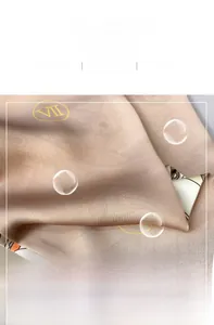 Vue macro d'un foulard en soie champagne montrant la texture douce et les imprimés