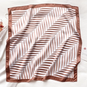 Detail of silk square scarf showing brown wavy geometric print and smooth texture