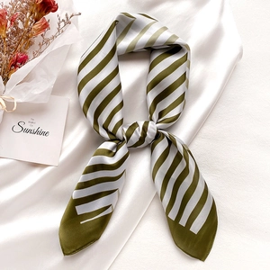 Olive green and white striped satin neck scarf tied in a bow on silk background