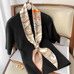 Détail d'un foulard en soie à motif horloge rétro noué sur un haut en tricot noir