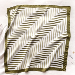 Detail of square silk scarf featuring olive green and white herringbone geometric patterns