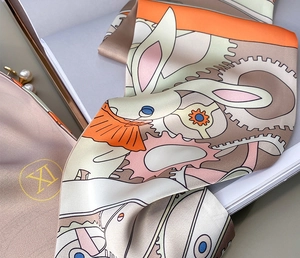 Détail d'un foulard en soie avec motifs de lapins et d'engrenages et pochette cadeau