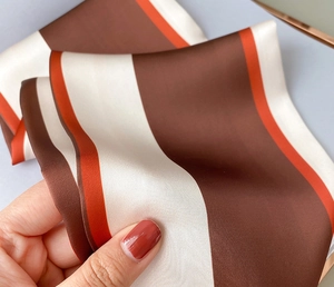 Detailaufnahme eines Seidenschals mit eleganten braunen, beigen und orangen Streifenmuster