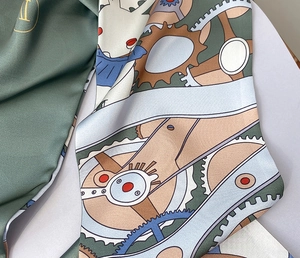 Gros plan du foulard en soie montrant un imprimé steampunk et lapin sur satin vert