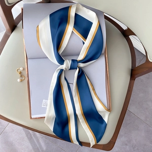 Eleganter Seidenschal mit blau-gelben Streifen auf einem grünen Sessel