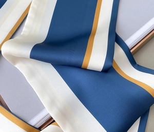 Detail eines Seidenschals mit Streifenmuster in Marineblau, Cremeweiß und Senfgelb