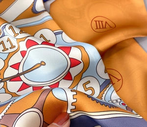 Gros plan d'un foulard en soie satinée au motif d'horloge orange avec coutures fines