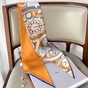 Détail d'un élégant foulard twilly en soie orange aux motifs d'horloge sur une chaise