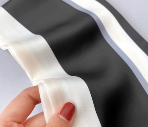 Makroaufnahme von glattem schwarz-weiß gestreiftem Satinstoff mit weicher Textur und Glanz