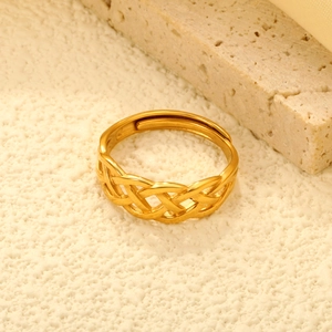 Detailed macro shot of a gold woven texture adjustable open ring on a textured background