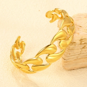 Detail of an irregular open cuff bracelet in 18K gold plated stainless steel on a rock