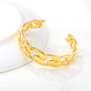 Close-up of golden Cuban link open cuff bracelet on white ceramic vessel edge