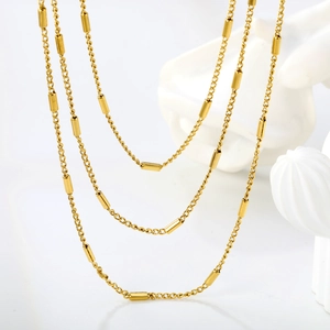 Elegante goldene Pulloverkette mit glatten Metallzylindern und feinem Kettengliederdesign