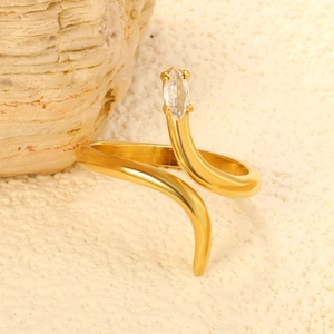 Macro shot of gold snake ring with marquise zircon on textured stone surface