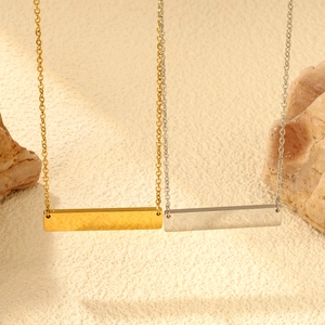 Minimalistische geometrische Stab-Halskette in Gold und Silber auf Stein-Hintergrund