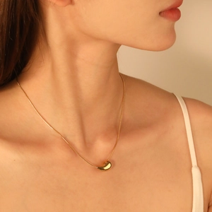 Elegant 18K gold plated stainless steel bean pendant necklace on a female model