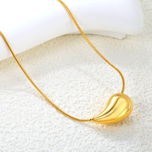 Macro shot of 18K gold plated teardrop pendant on a sleek snake chain over stone