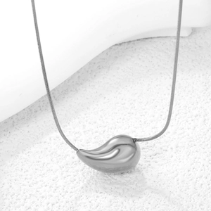 Macro shot of silver teardrop pendant on a sleek snake chain with high-polish finish