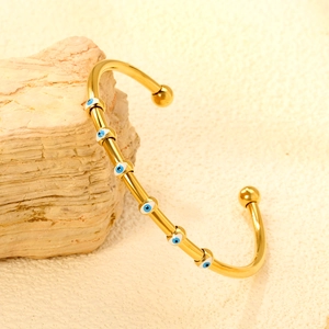 Gold-plated stainless steel evil eye open cuff bracelet on a natural stone base