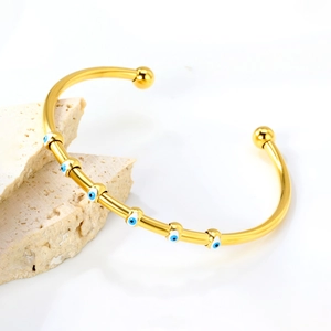 Bracelet jonc ouvert doré orné de six breloques œil bleu en émail sur métal poli