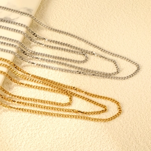 Layered 18K gold and silver curb chain necklaces on an elegant marble tray