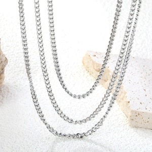 Minimalist silver stainless steel curb chain necklace layered on natural stone backdrop