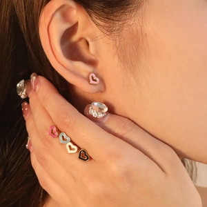 Detail shot of heart-shaped colorful enamel earrings in pink, blue, white, and black