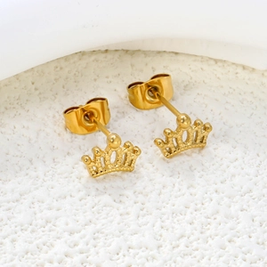Macro shot of gold-plated stainless steel crown stud earrings on white stone surface