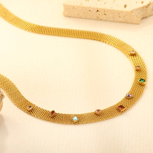 Vue macro d'un collier en maille dorée orné de pierres précieuses multicolores