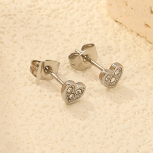 Elegante silberne Herz-Ohrstecker mit funkelnden Kristallen auf strukturierter Steinfläche