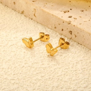 Polished 18K gold plated stainless steel butterfly stud earrings on textured stone