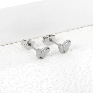 Macro shot of polished stainless steel butterfly stud earrings on a stone base
