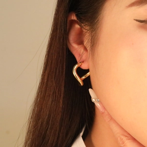 Boucle d'oreille cœur dorée au design torsadé portée par un mannequin femme
